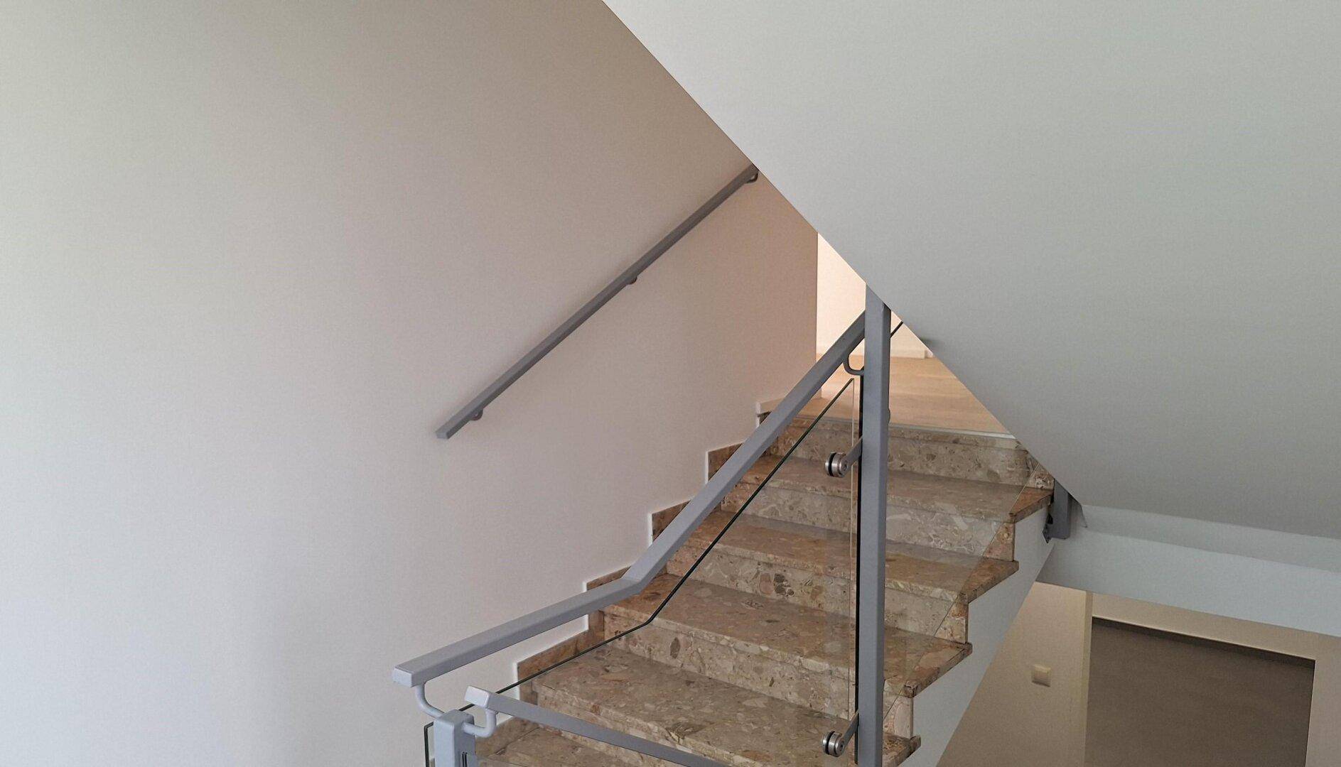 Heller Treppenaufgang mit Marmorstufen und modernem Glasgeländer in einem gepflegten Zustand.