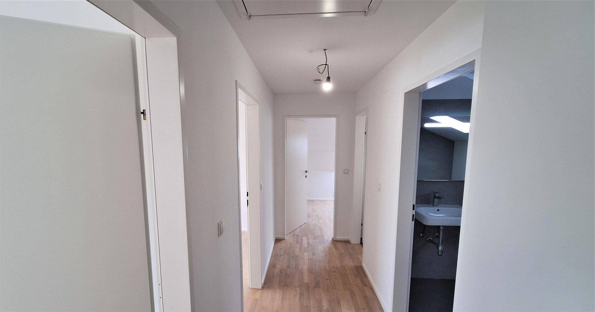 Geräumiger Flur im Dachgeschoss mit Parkettboden und Blick in ein angrenzendes Badezimmer.