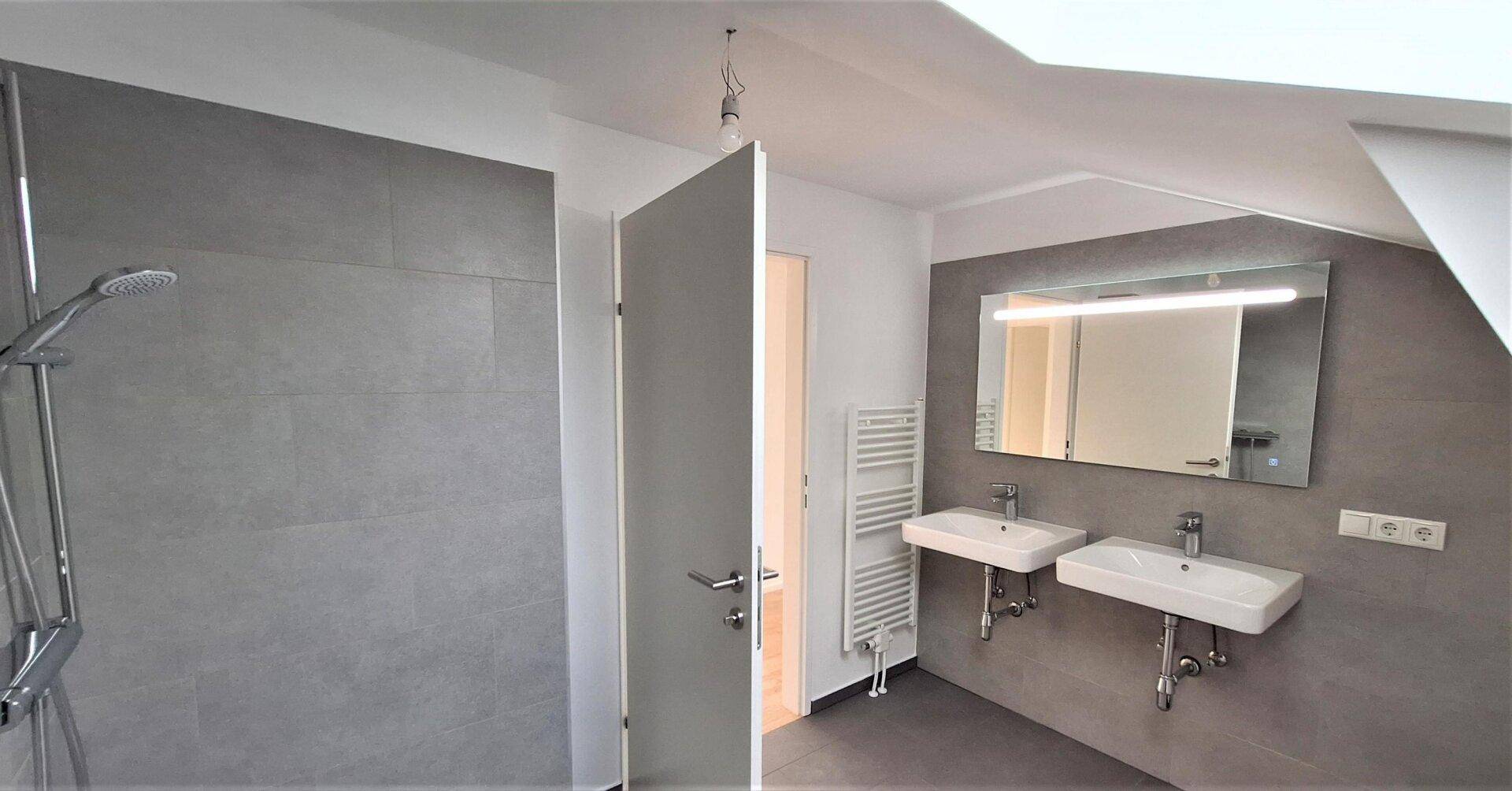 Modernes Badezimmer im Dachgeschoss mit Doppelwaschbecken, Dusche und beheiztem Handtuchhalter.