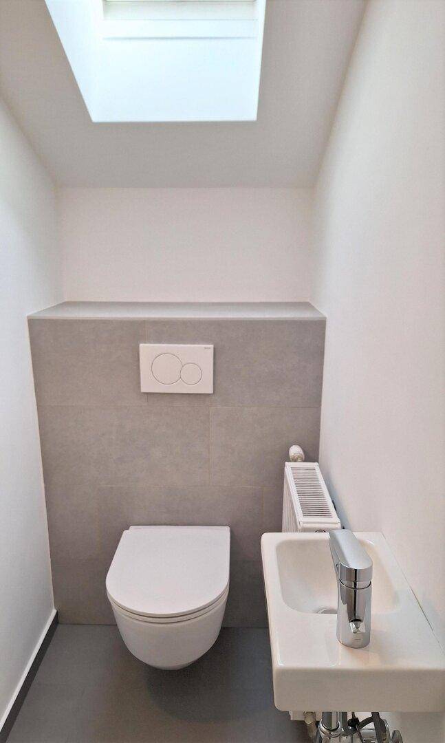 Kleines Gäste-WC im Dachgeschoss mit wandhängender Toilette, Waschbecken und Dachfenster.