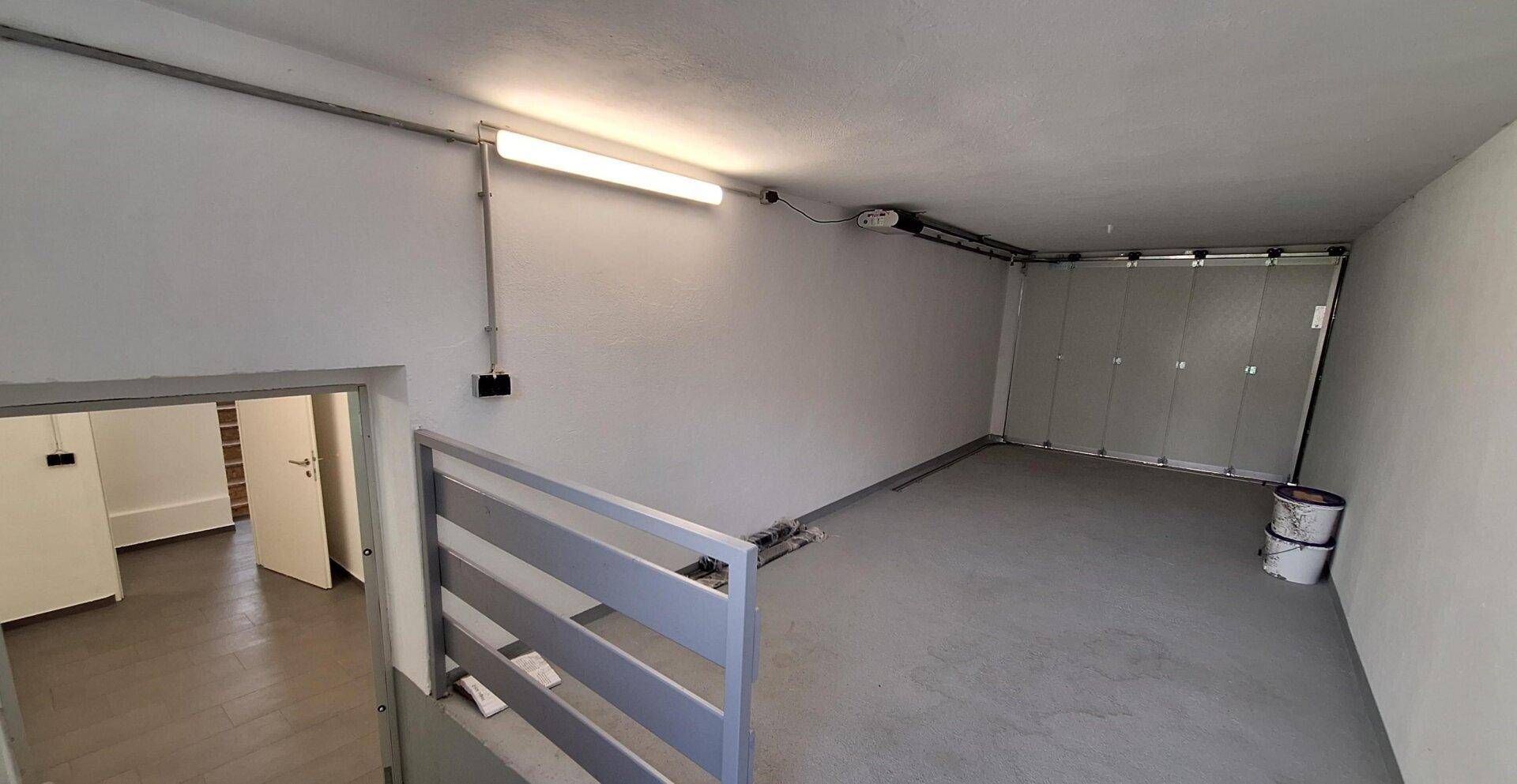 Geräumige Garage mit Betonboden, automatischem Tor und Zugang zum Innenbereich des Hauses.