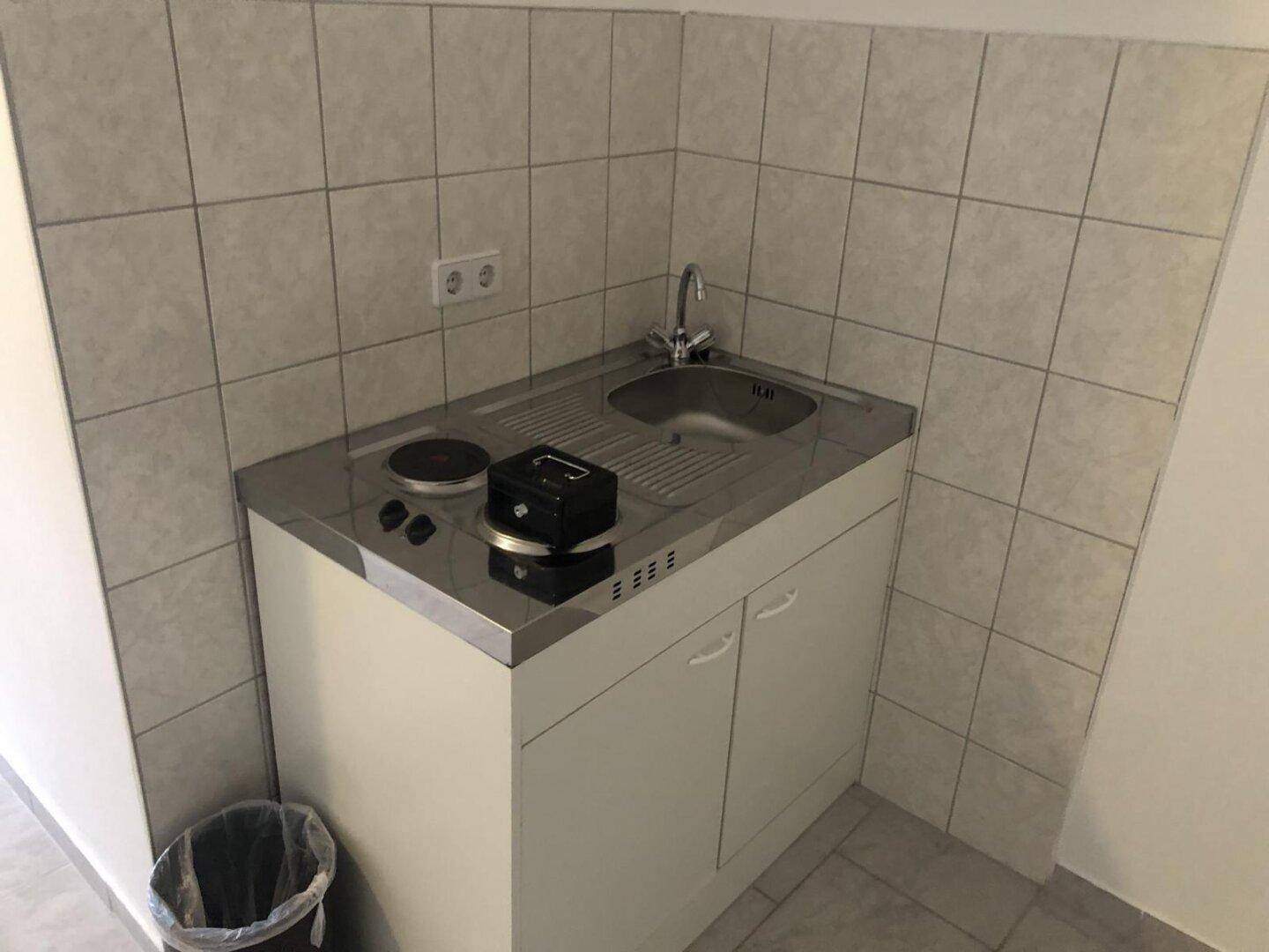Kompakte Küchenzeile mit Spüle, zwei Kochplatten und Unterschränken.