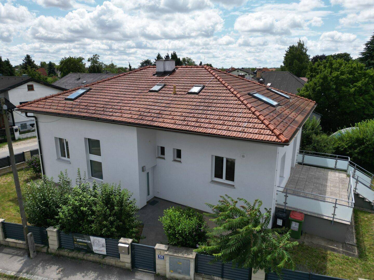 Ansicht des Einfamilienhauses von oben mit Ziegeldach und Dachfenstern in einer Wohnsiedlung.