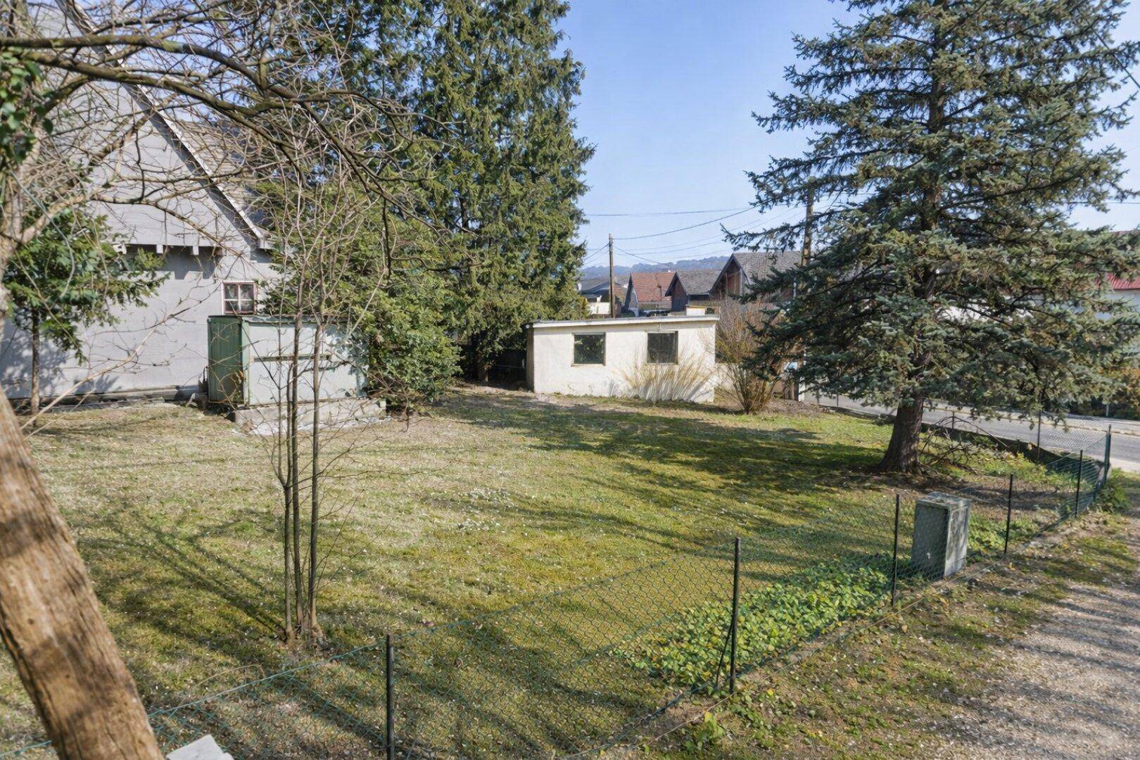 Weitläufiger Garten mit Rasen, Bäumen und Blick auf die umliegende Bebauung.