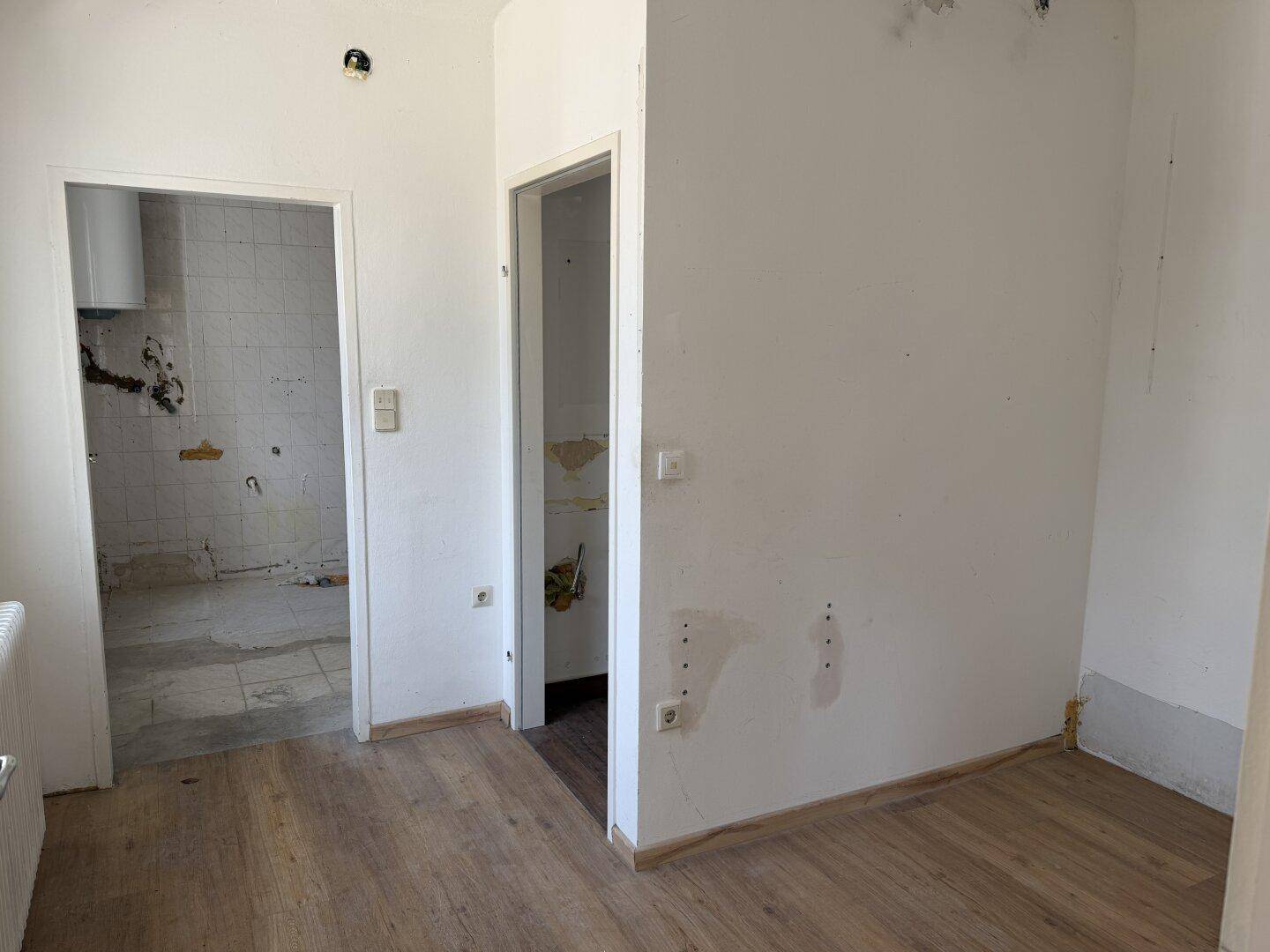 Flur mit Laminatboden und Zugängen zu weiteren Räumen, die renoviert werden.