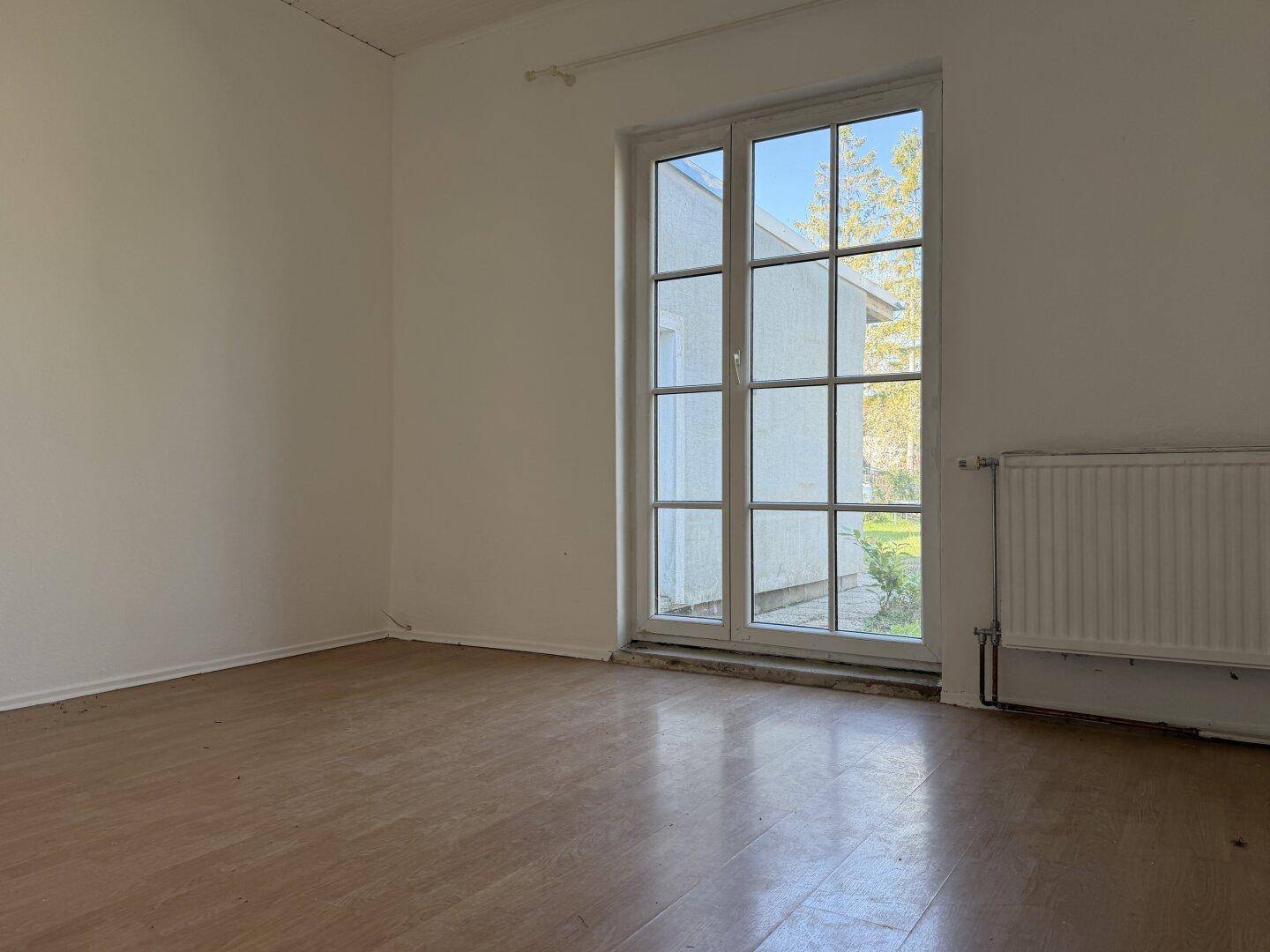 Helles Schlafzimmer im Renovierungszustand mit Laminatboden und großer Fenstertür.