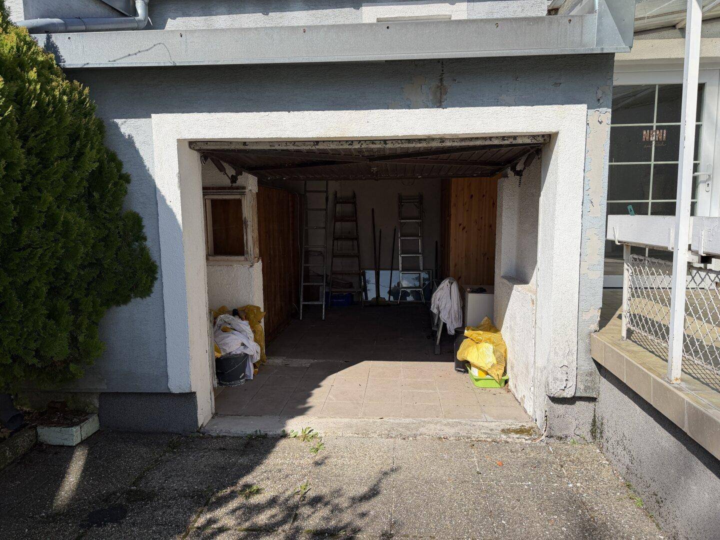 Offene Garage mit Stauraum und Leitern, die auf eine Renovierung hindeutet.