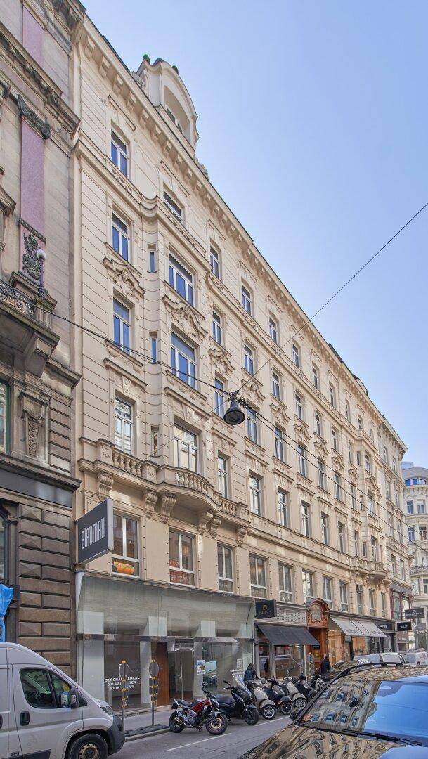Historisches Gebäude mit klassischer Fassade, vielen Fenstern und Geschäften im Erdgeschoss.