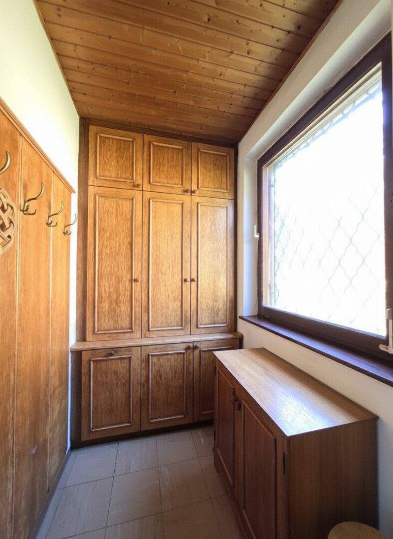 Eingangsbereich mit Holzschränken, Holzdecke und Fenster mit Gittermuster.