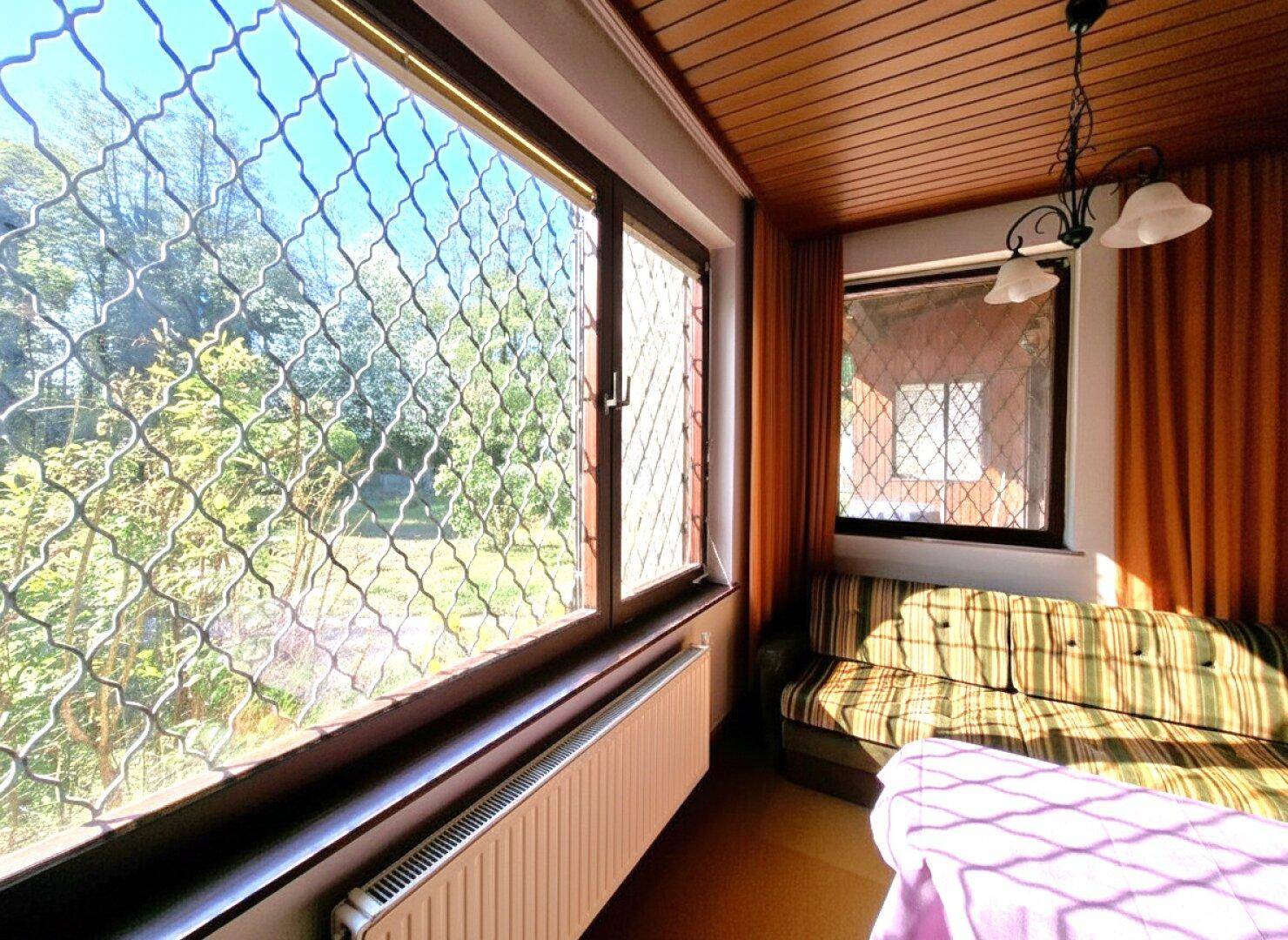 Großes Fenster im Wohnzimmer mit Blick auf den Garten und viel Tageslicht.