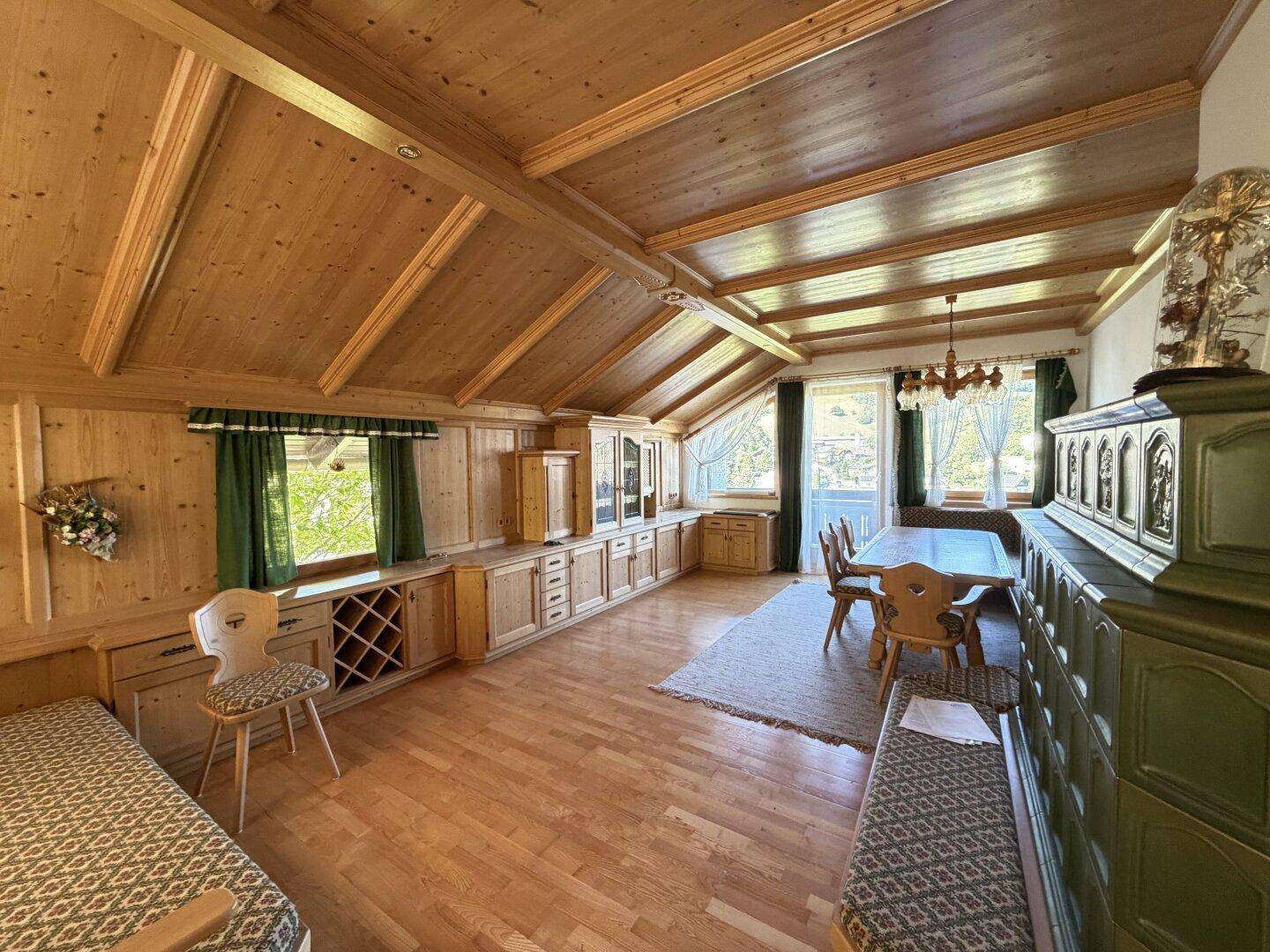 Gemütlicher Wohn-Essbereich im alpinen Stil mit Holzbalkendecke, Parkettboden und traditionellen Möbeln.