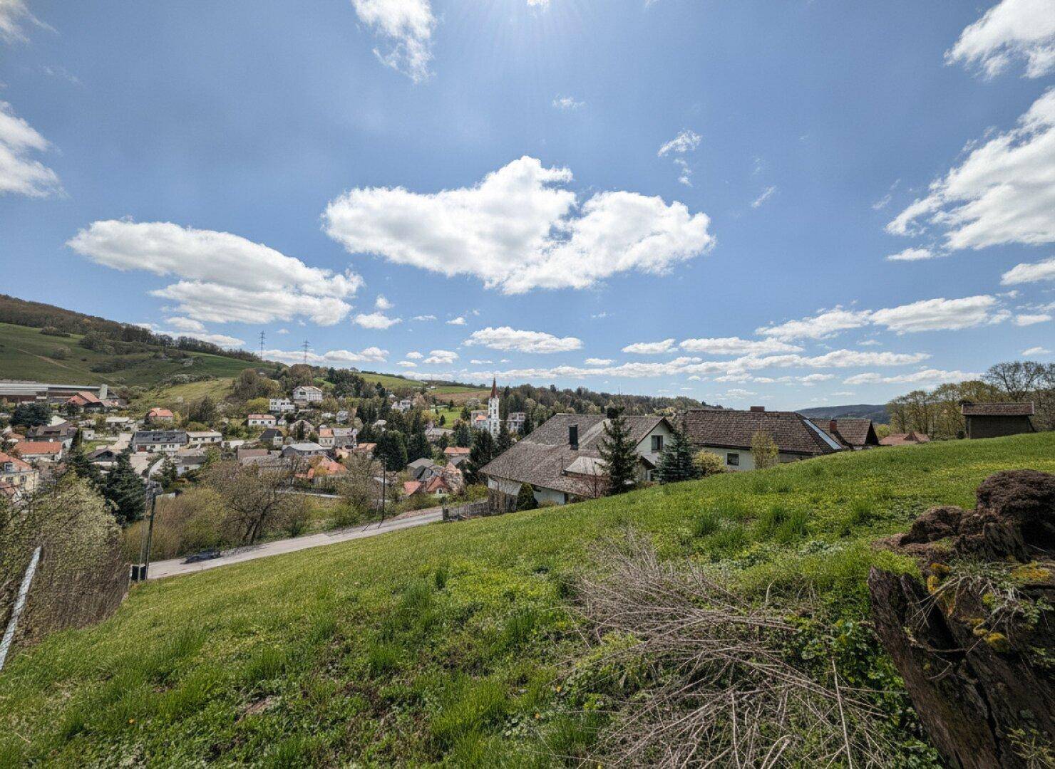 Sonniges Hanggrundstück mit weitem Blick über das Tal und die umliegende Ortschaft.