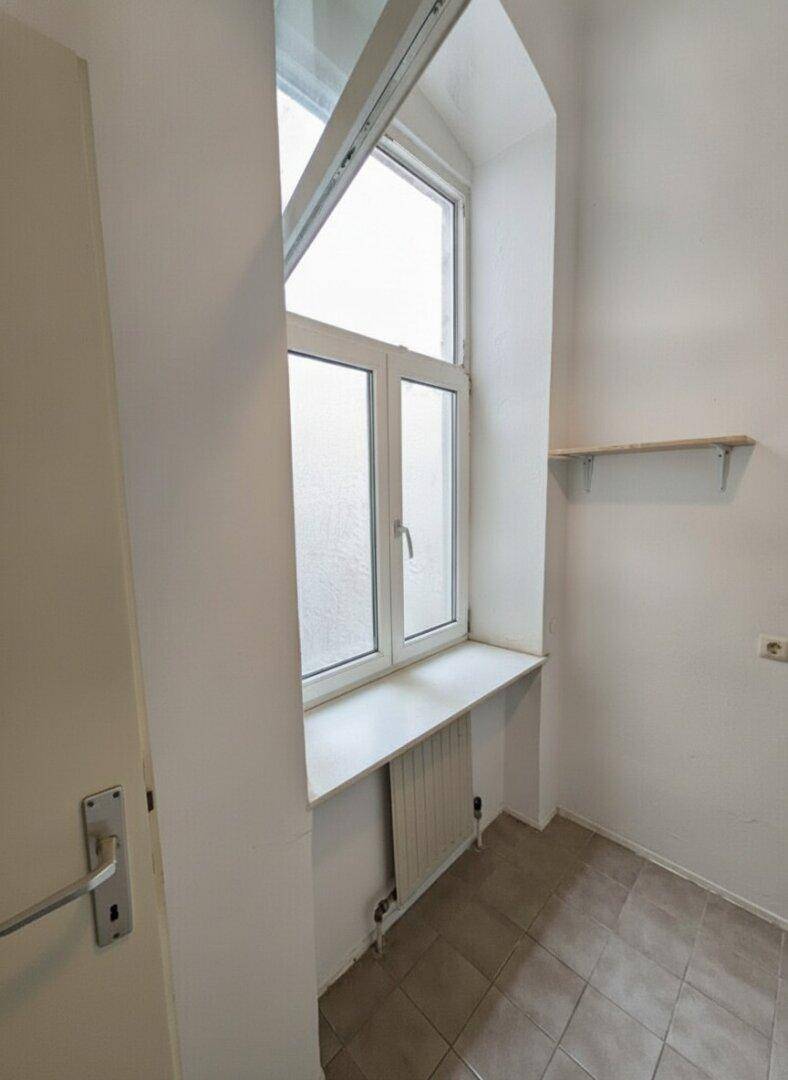 Kleiner Raum mit Fenster, Heizkörper und Fliesenboden, möglicherweise als Abstellraum nutzbar.