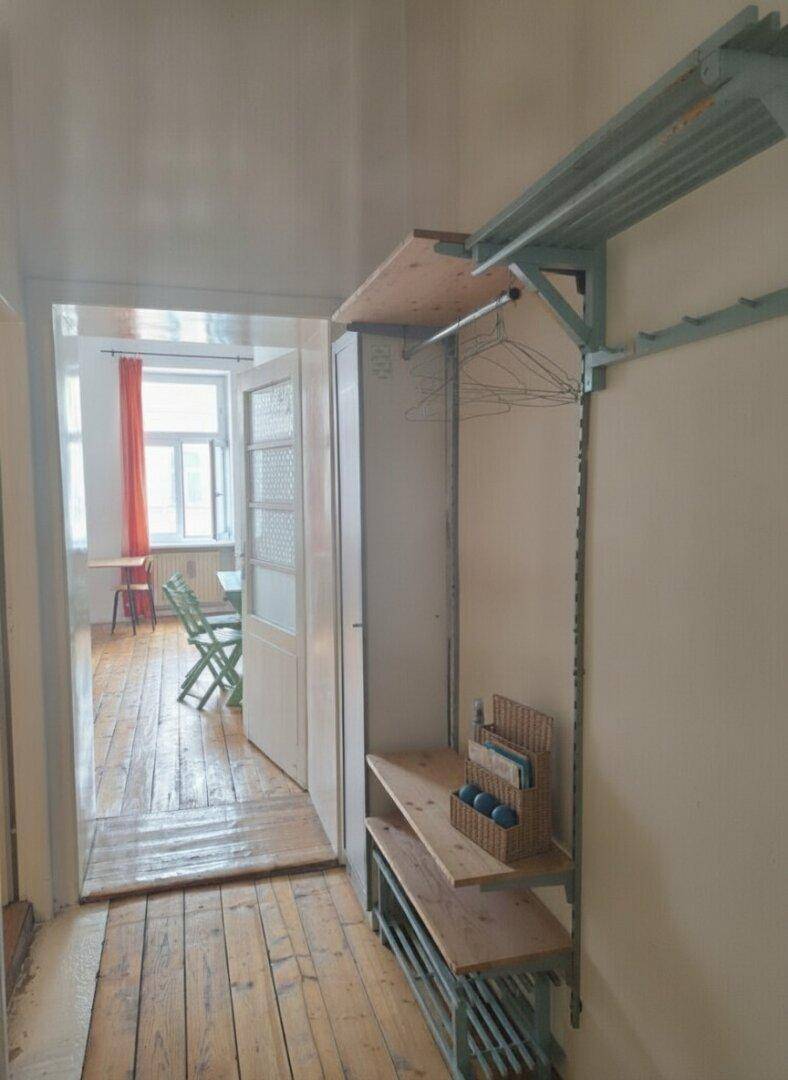 Flur mit Holzdielenboden und Blick in ein helles Wohnzimmer.