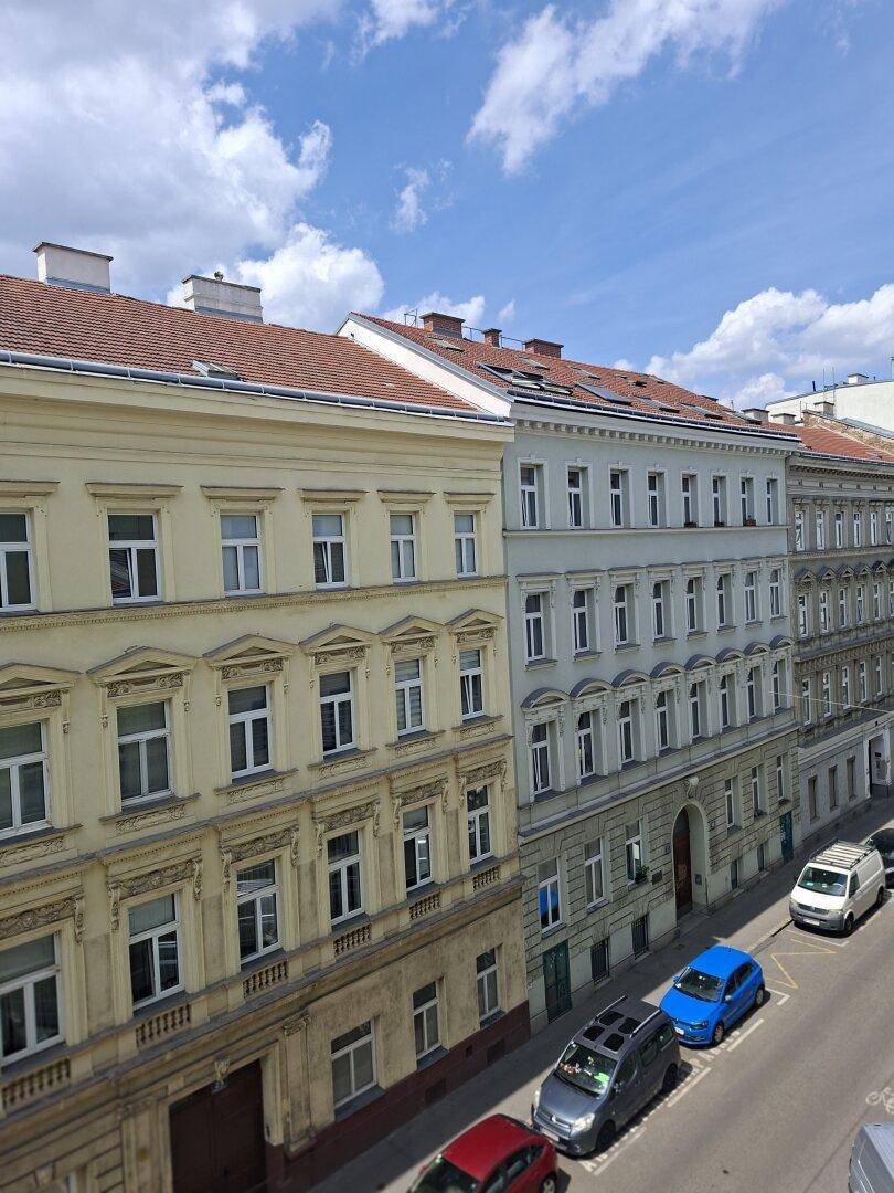 Historische Gebäude entlang einer Straße unter blauem Himmel mit Wolken.
