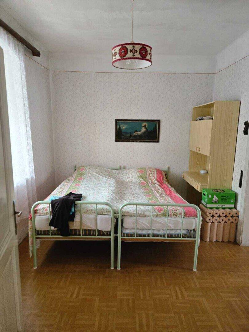 Schlafzimmer mit zwei Einzelbetten, Holzparkett und einfacher Einrichtung.
