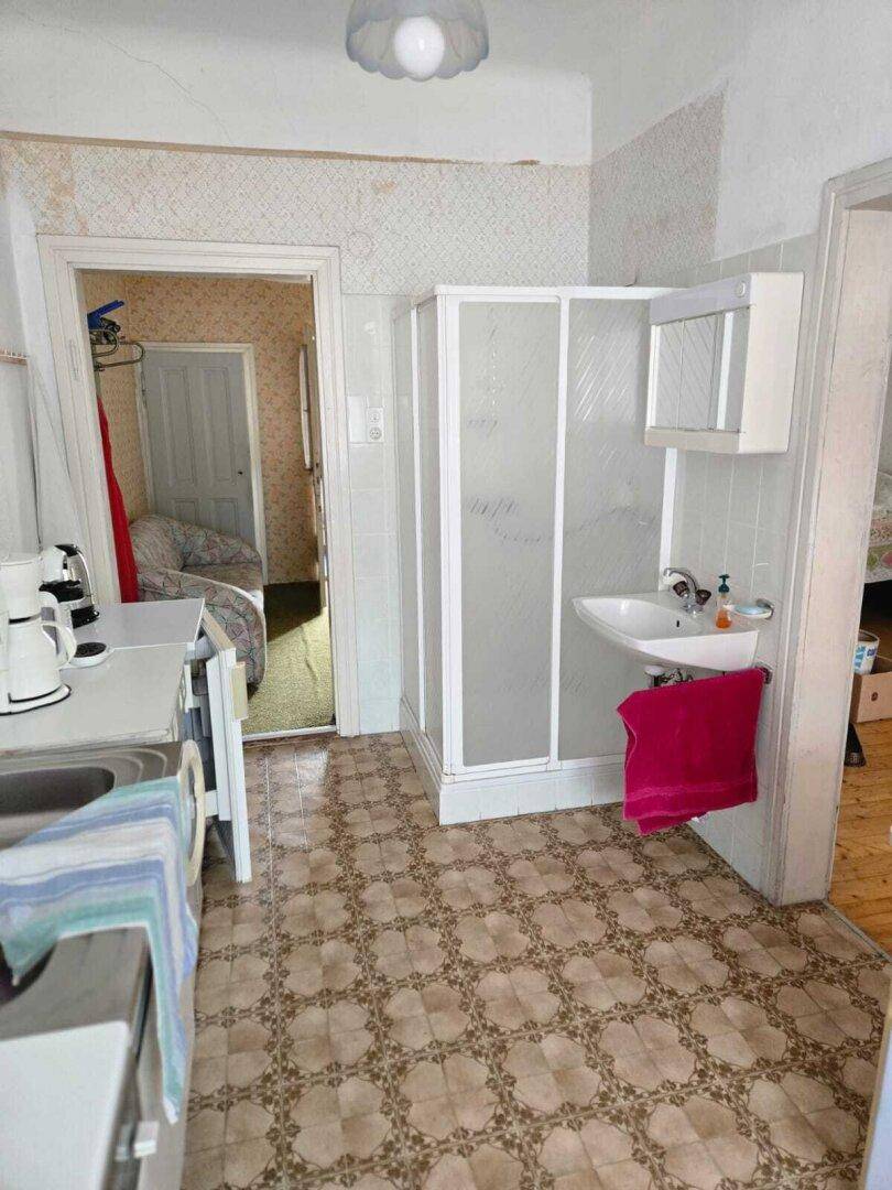 Kleines Badezimmer mit Duschkabine, Waschbecken und gemustertem Fliesenboden.