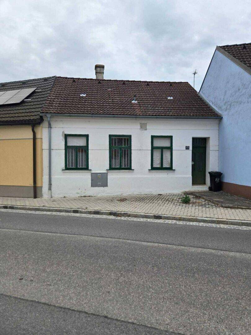 Einfamilienhaus von der Straße aus gesehen mit traditioneller Architektur und grünen Fensterrahmen.