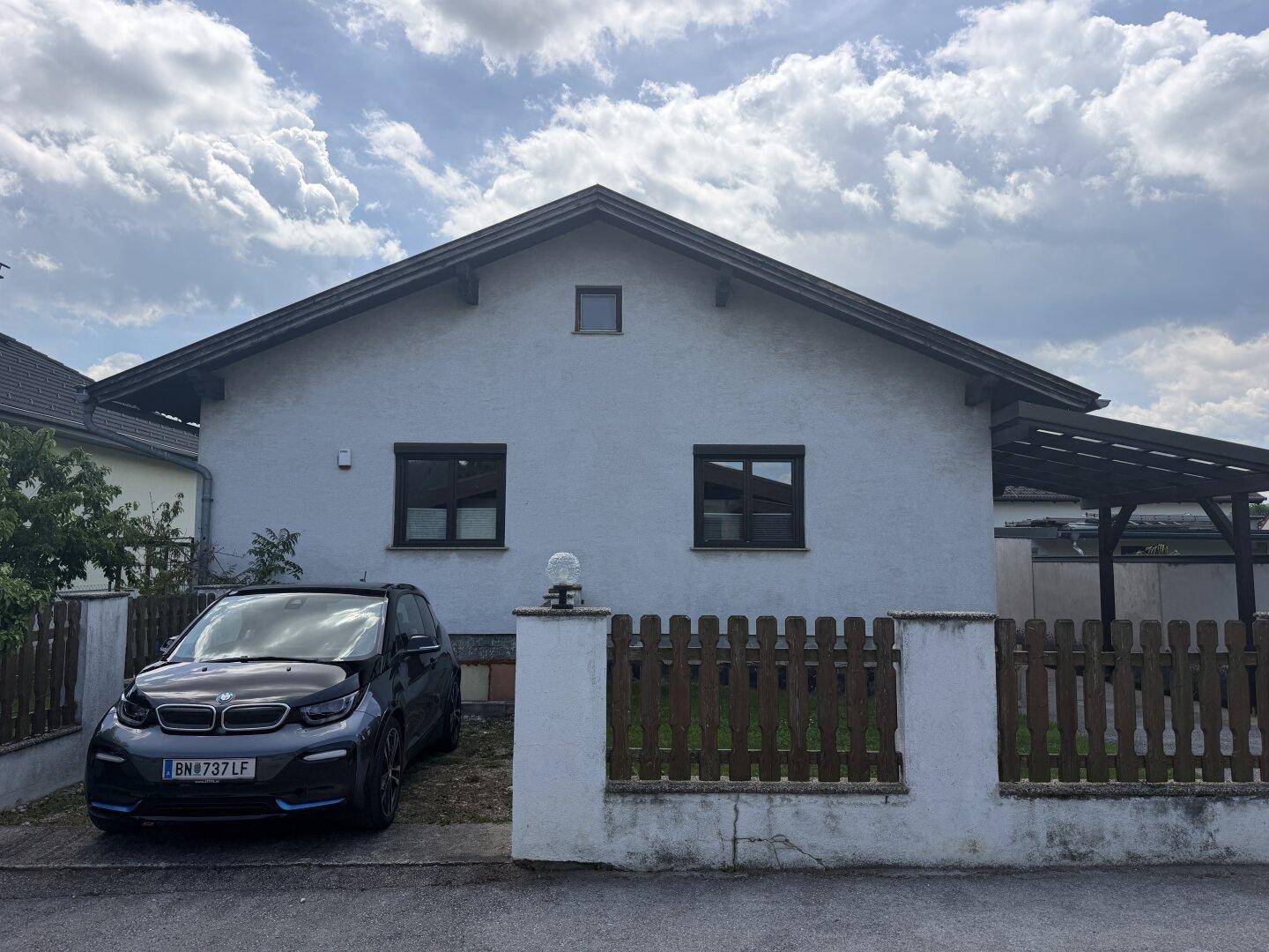 Einfamilienhaus mit Satteldach, weißer Fassade und Carport.