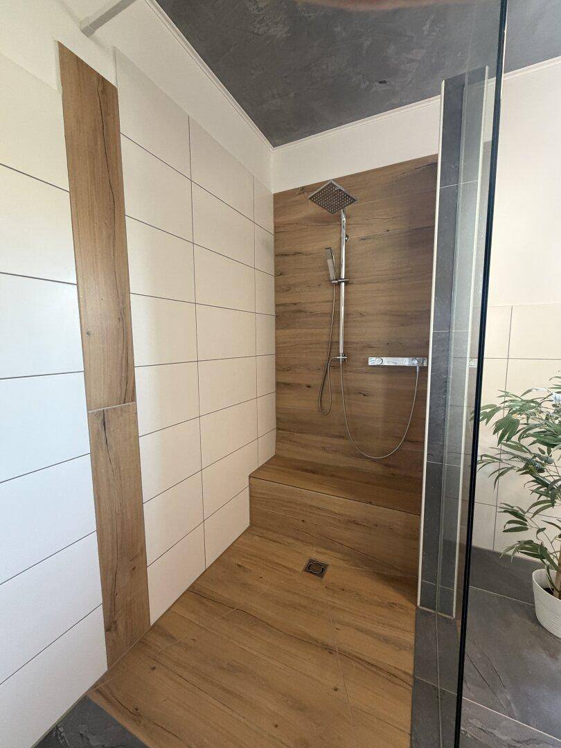 Elegante begehbare Dusche mit Holzoptik-Fliesen und Regenduschkopf.