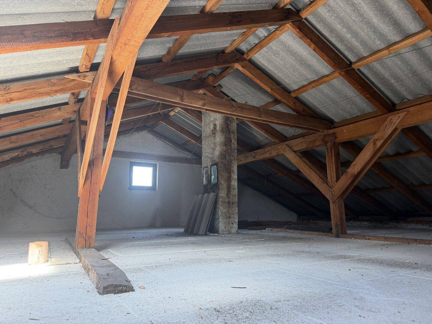 Geräumiger, unausgebauter Dachboden mit freiliegenden Holzbalken und viel Tageslicht.