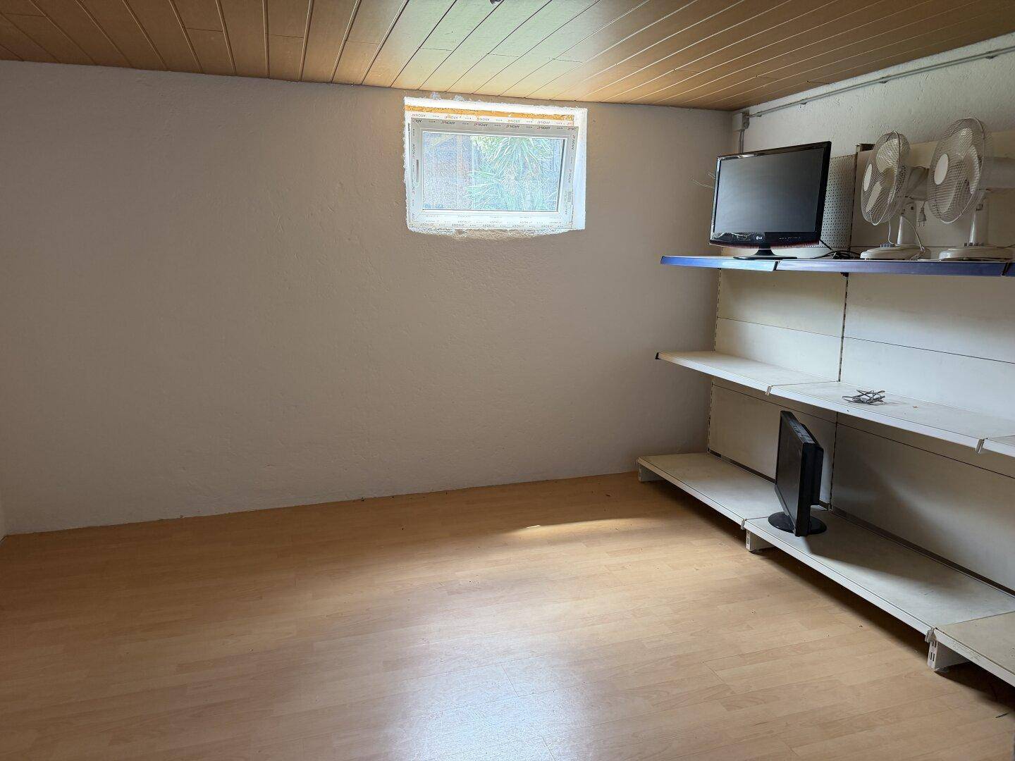 Kellerraum mit Holzdecke, Laminatboden und Regalen.