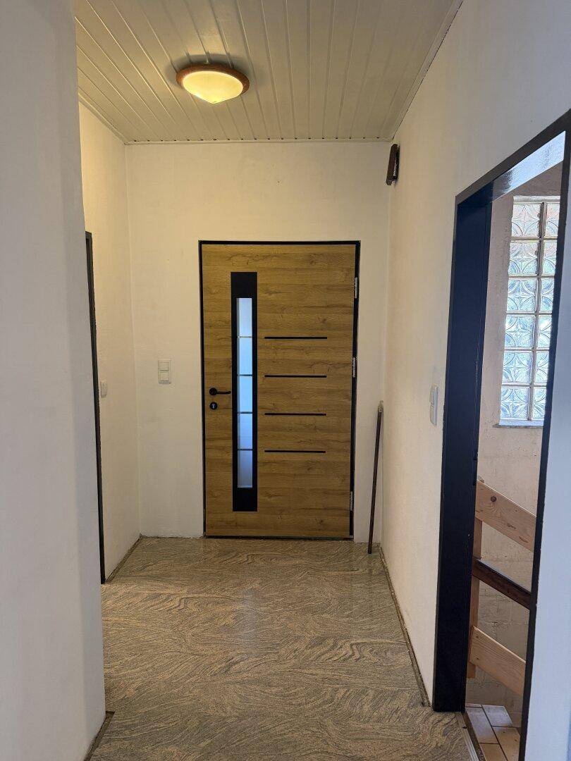 Eingangsbereich mit moderner Holztür und gemustertem Fliesenboden.