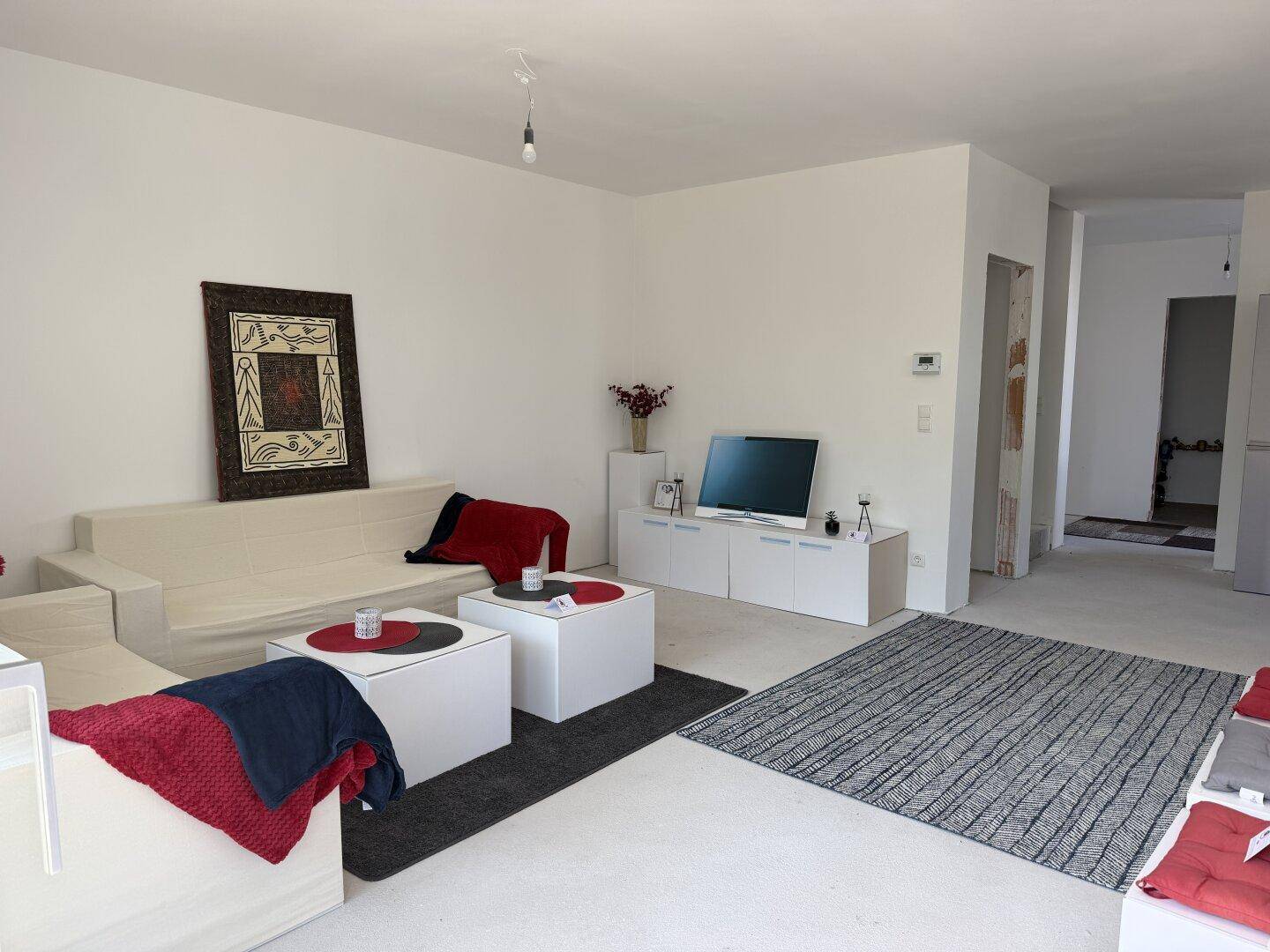 Gemütlicher Wohnbereich mit hellem Sofa, modernen Couchtischen und einem Teppich, einladend und funktional.