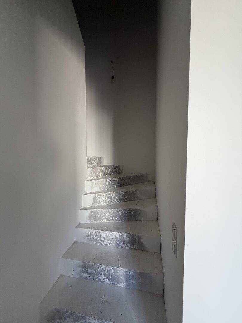 Unfertige Treppe in einem hellen Treppenhaus, das in die obere Etage führt, noch im Bau.