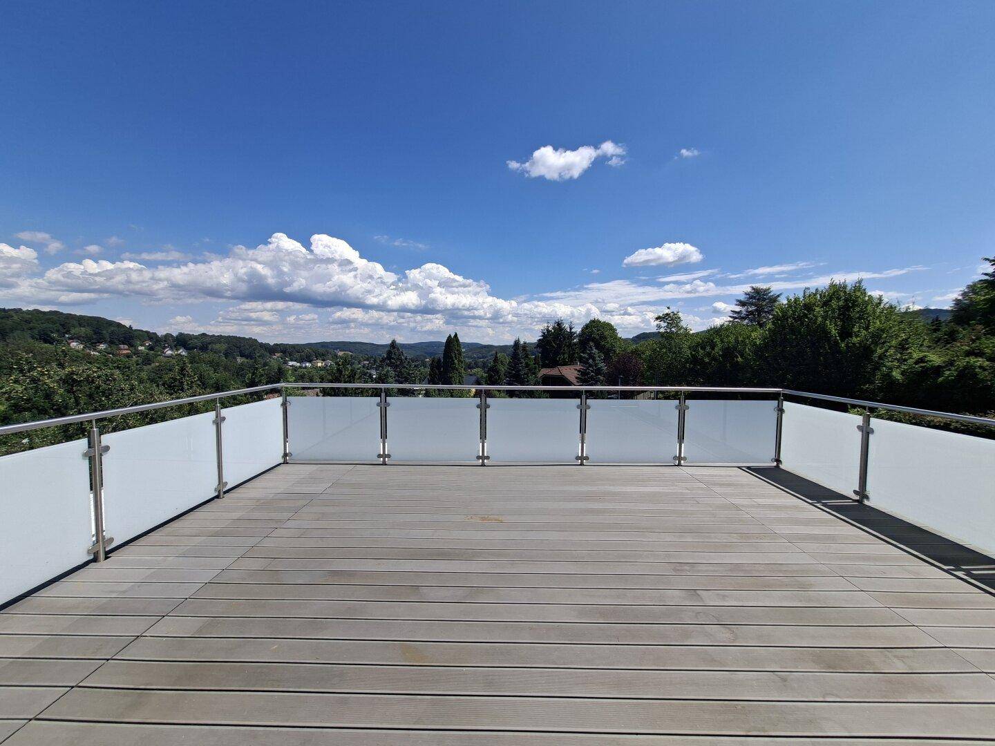 Geräumige Dachterrasse mit modernem Glasgeländer und weitem Panoramablick über die Landschaft.