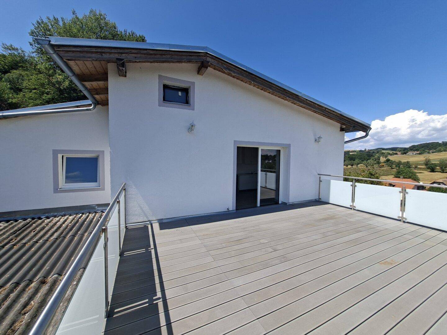 Große Dachterrasse mit modernem Geländer und Zugang zum Innenbereich des Hauses.
