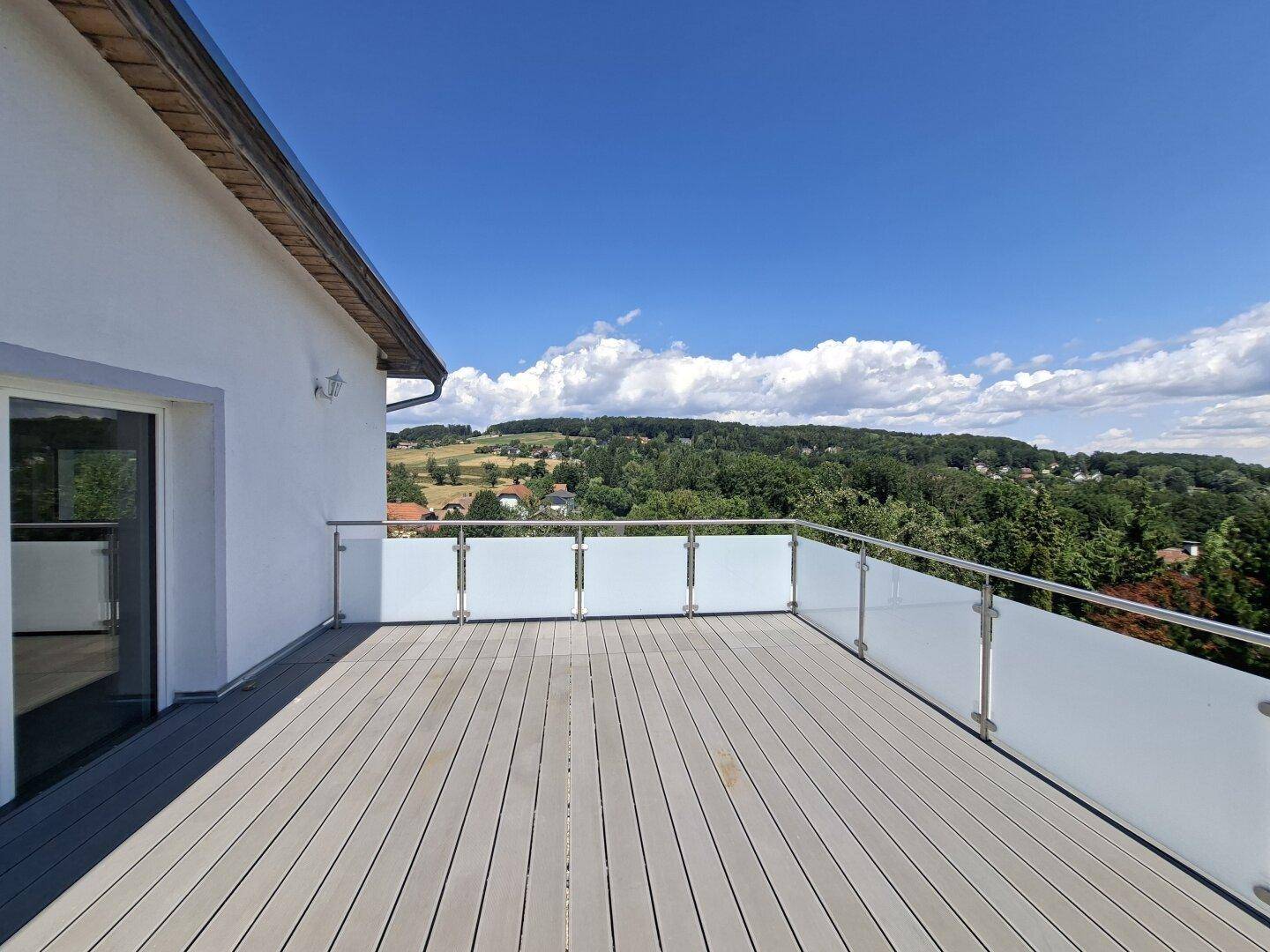 Weitläufige Dachterrasse mit Panoramablick auf die grüne Landschaft und den Horizont unter blauem Himmel.