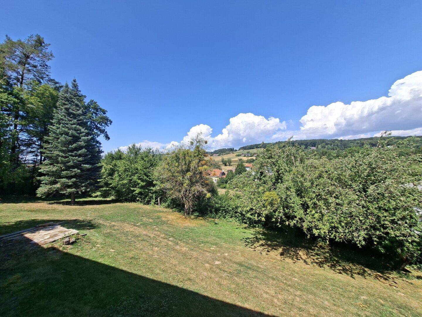 Weitläufiger Garten mit altem Baumbestand und einem schönen Blick auf die umliegende Landschaft.