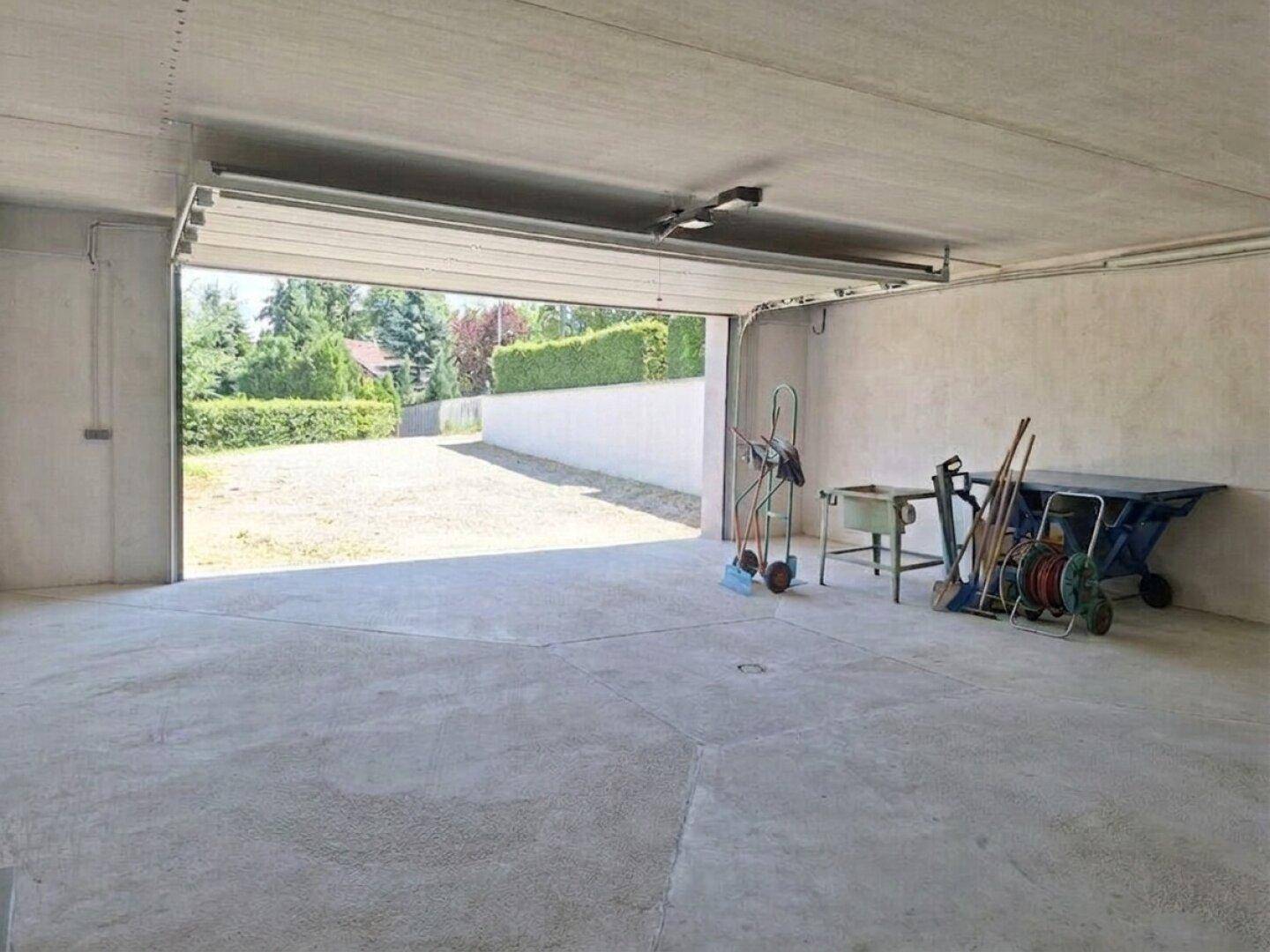 Große Garage mit offenem Tor, das den Blick auf den sonnigen Außenbereich freigibt.