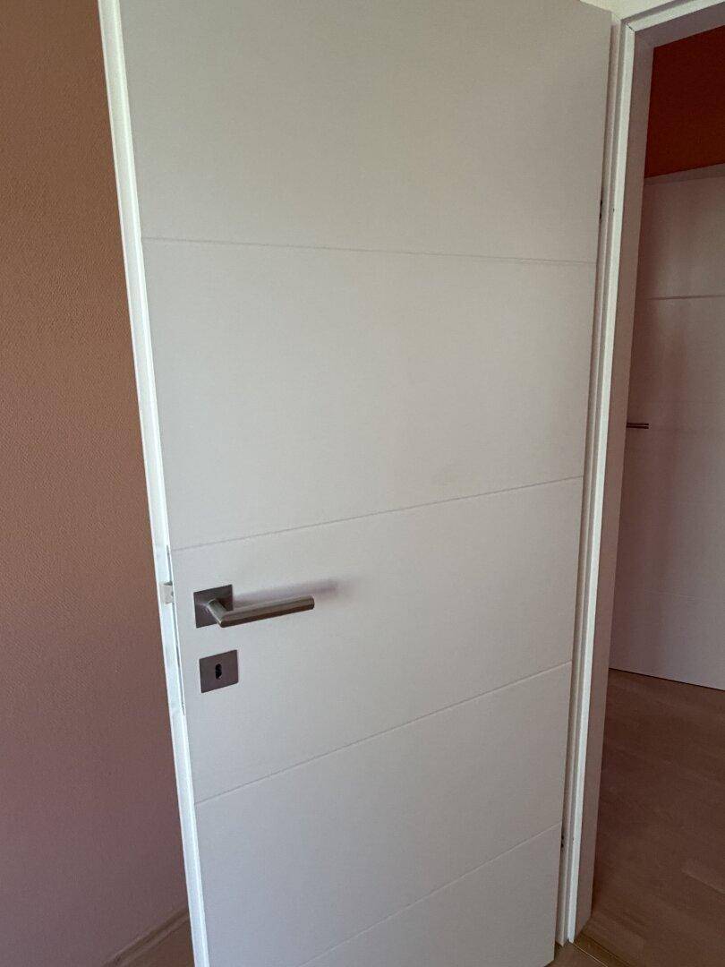 Moderne weiße Innentür mit horizontalen Linien und elegantem Griff.
