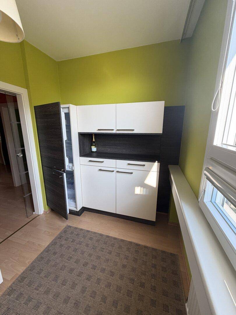 Erweiterter Küchenbereich mit integriertem Kühlschrank und weiteren weißen Schränken, passend zur Hauptküche.
