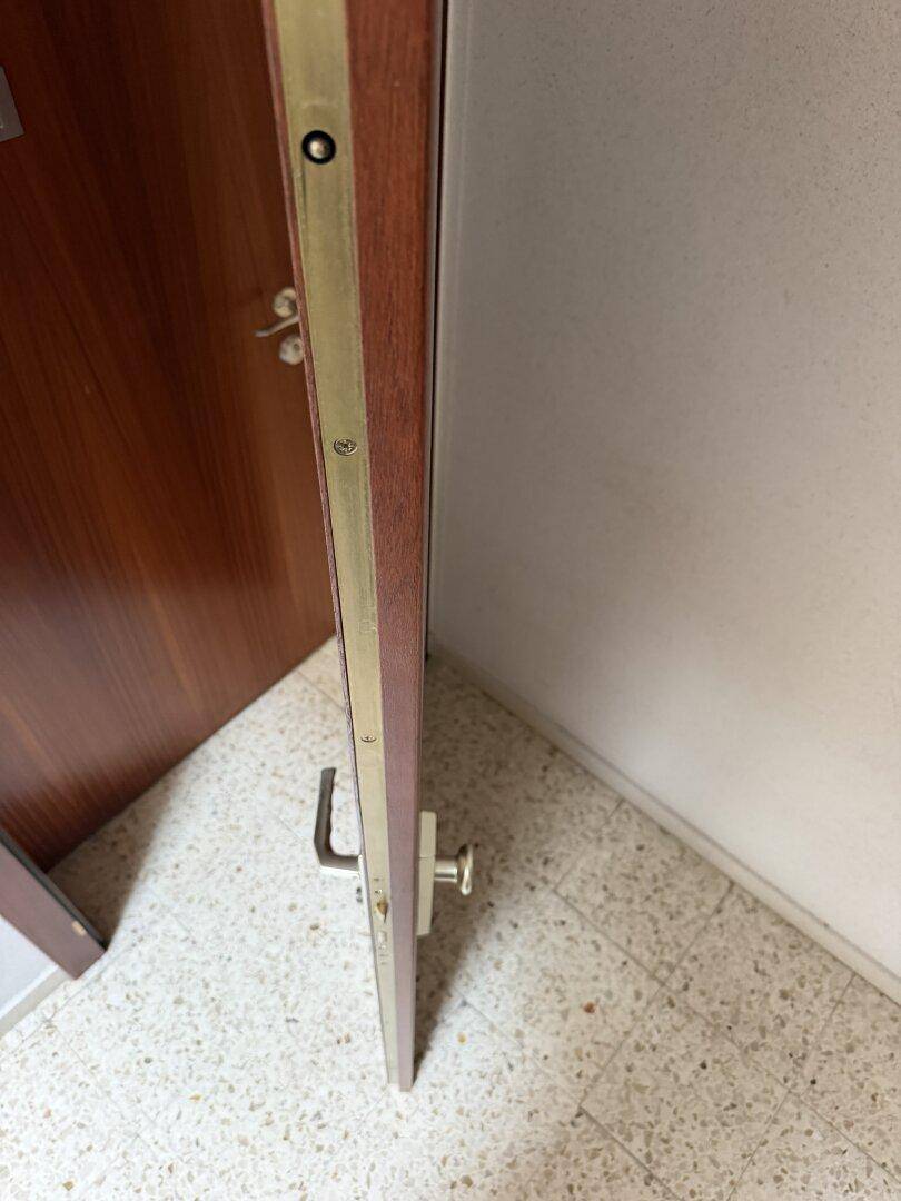 Detailansicht des Türrahmens mit Metallleiste und einem Teil des gefliesten Bodens.