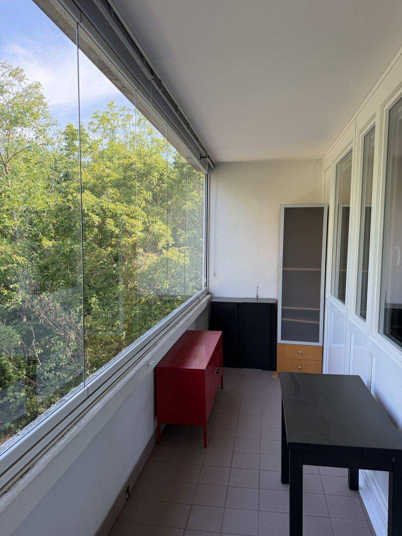 Verglaste Loggia mit Möbeln und weitem Blick ins Grüne, ideal für Entspannung.