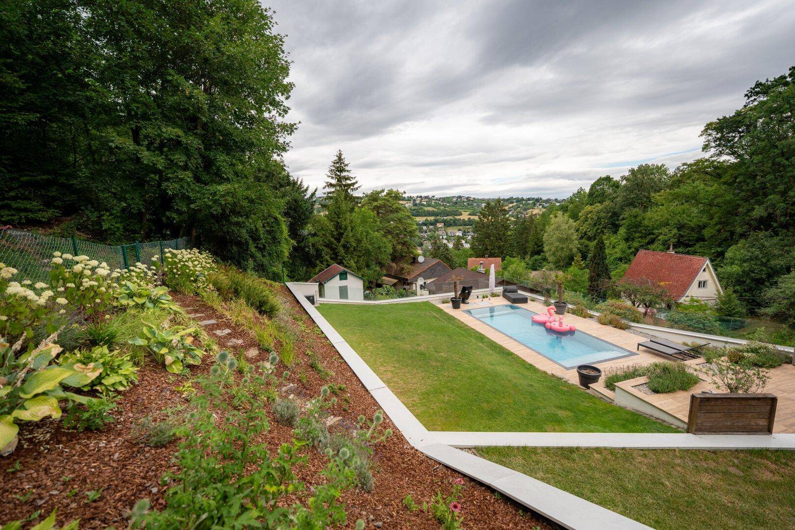 Weitläufiger Gartenbereich mit Pool, Rasenflächen und einem malerischen Ausblick über die Landschaft.