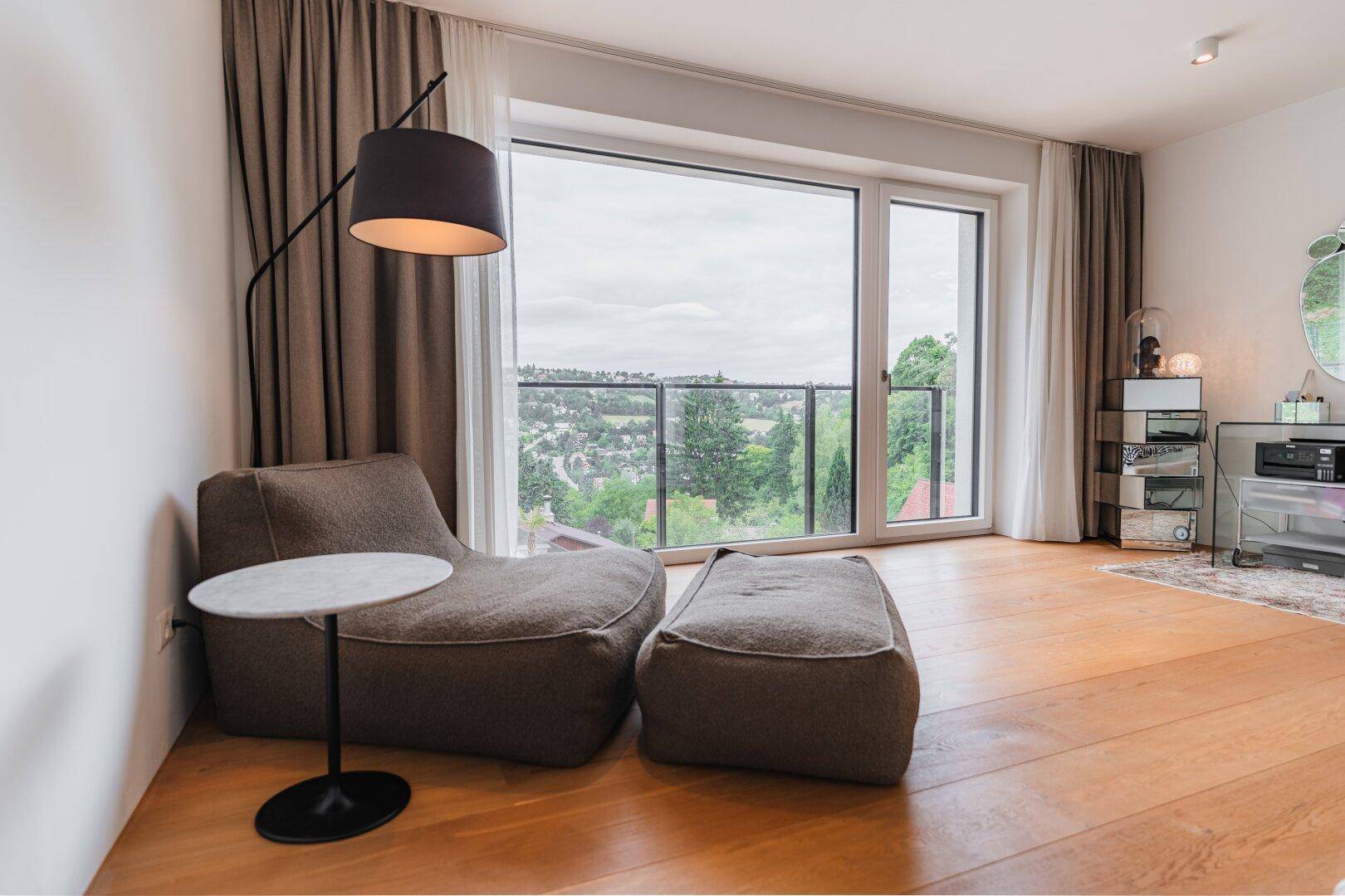 Gemütliche Leseecke mit großem Fenster, Holzboden und weitem Blick ins Grüne.