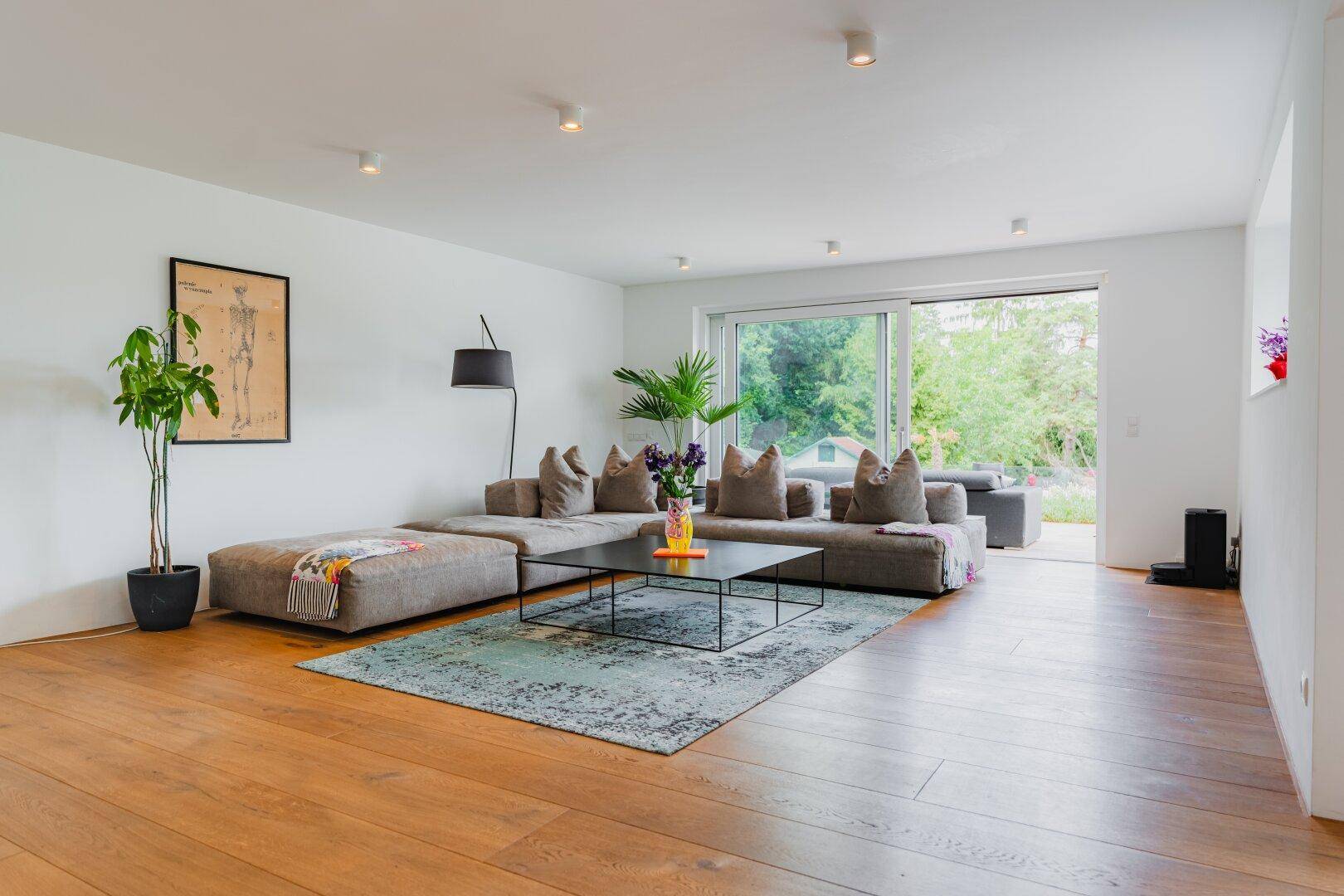 Helles und geräumiges Wohnzimmer mit großem Sofa, Holzboden und Zugang zur Terrasse.