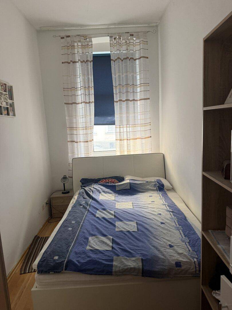 Kleines Schlafzimmer mit Einzelbett und Fenster, das für ausreichend Tageslicht sorgt.