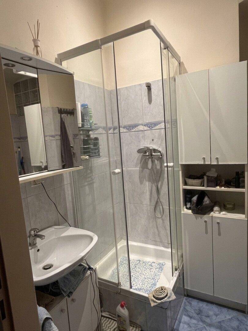 Badezimmer mit Duschkabine, Waschbecken und Spiegelschrank, ausgestattet mit blauen Fliesen.