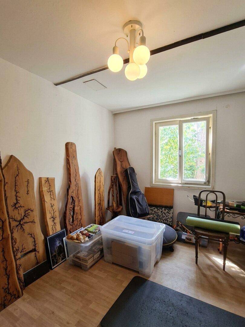 Heller Raum mit Holzböden und Fenster, derzeit als Lager- oder Hobbyraum genutzt.