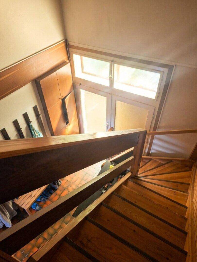 Holztreppe mit natürlichem Lichteinfall von oben, die in das obere Stockwerk führt.