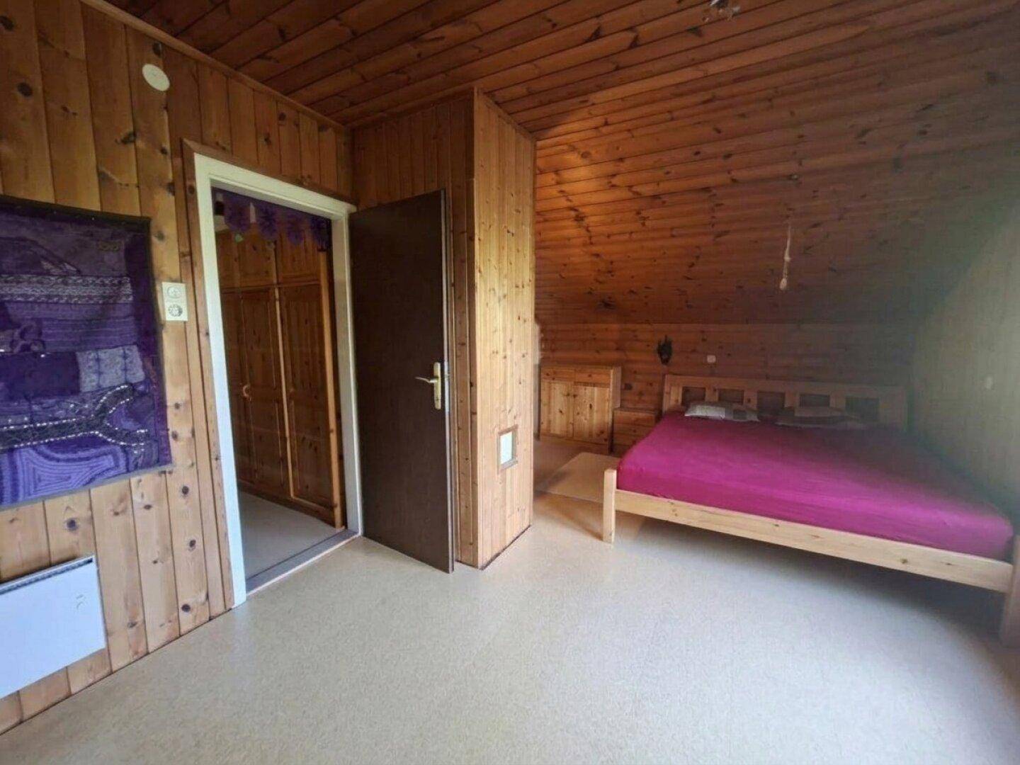 Schlafzimmer mit Holzwänden, Holzdecke und einem Doppelbett.