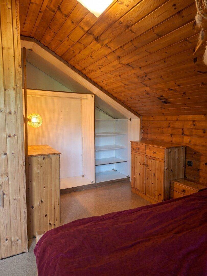 Schlafzimmer mit Holzwänden, Dachschräge und integriertem Stauraum.