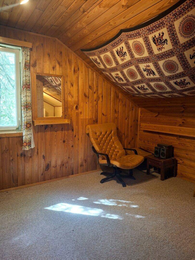 Raum mit Holzwänden, Teppichboden und einem Sessel, ideal als Arbeits- oder Leseecke.