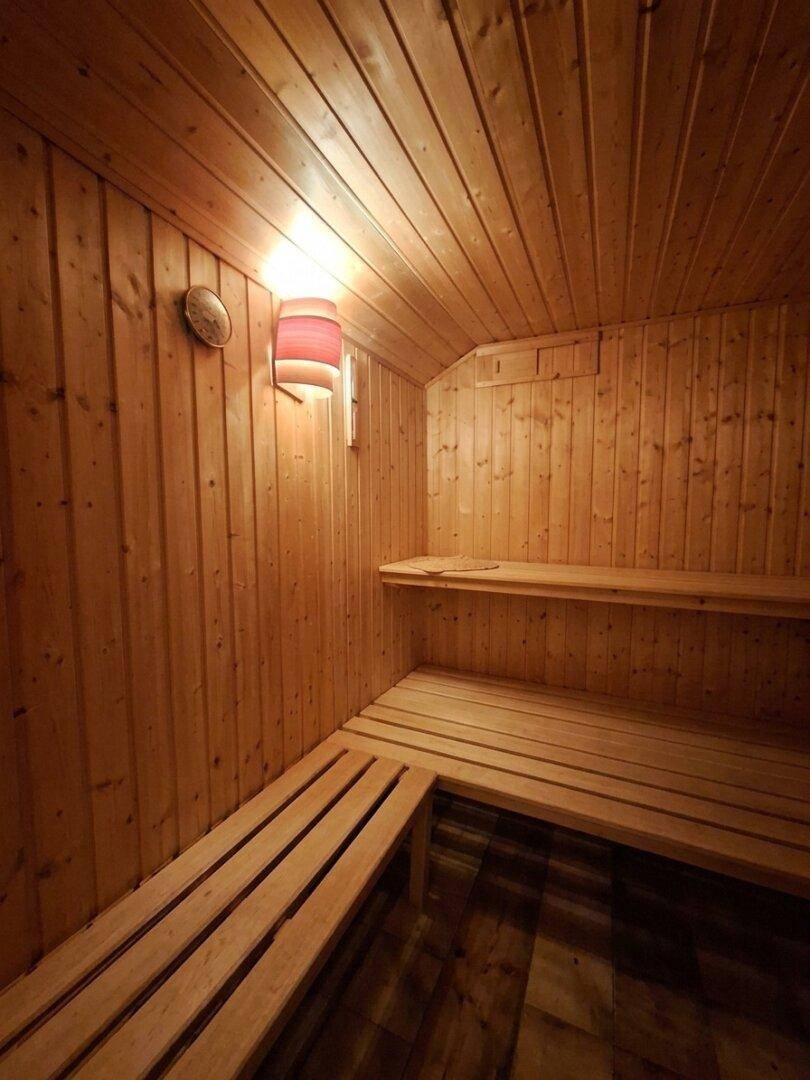 Holzvertäfelte Sauna mit Sitzbänken und stimmungsvoller Beleuchtung für Entspannung.