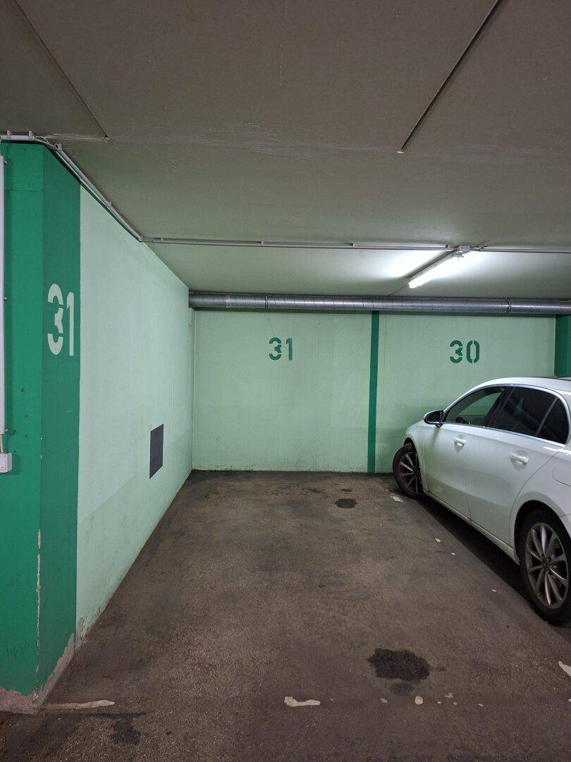 Tiefgarage mit grünen Wänden, nummerierten Parkplätzen und einem geparkten Auto.
